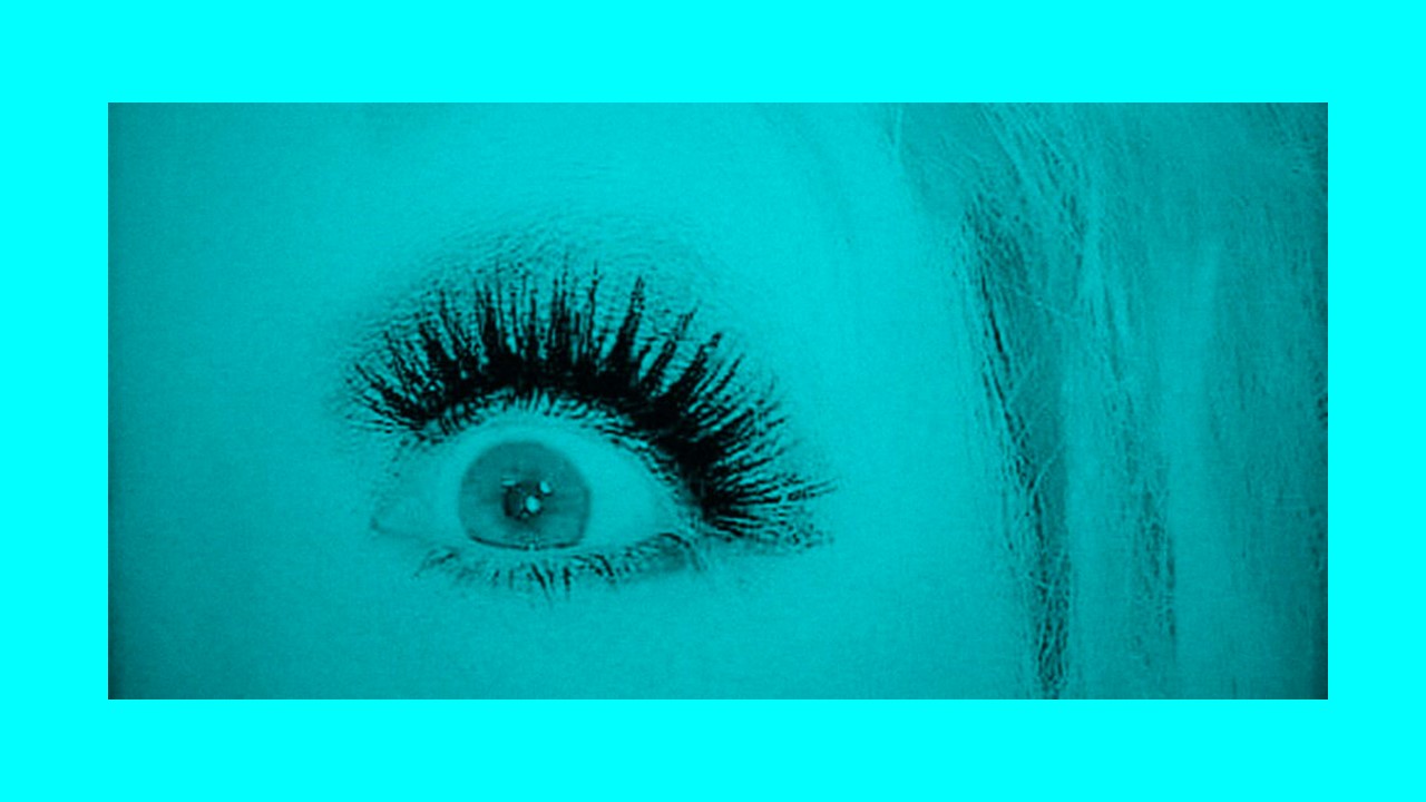 a close up on a woman's eye. Heavily made up and false eyelash. A turquoise coloured image and border.